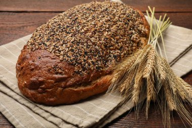 Tahta masada bir somun taze ekmek ve buğday çivisi, yakın plan.