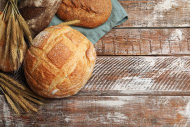 Tahta masada taze ekmek ve buğday dikenleri düz yerde. Metin için boşluk