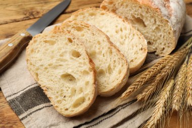 Taze ekmek, buğday başakları ve bıçak ahşap masada, yakın plan.