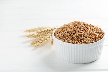 Kasede buğday taneleri, beyaz ahşap masada çiviler, yakın plan. Metin için boşluk