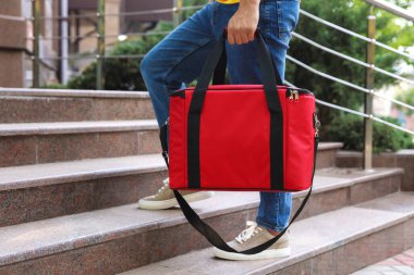 Dışarıdaki merdivenlerde termo çantalı kurye, yakın plan. Yemek dağıtım servisi.