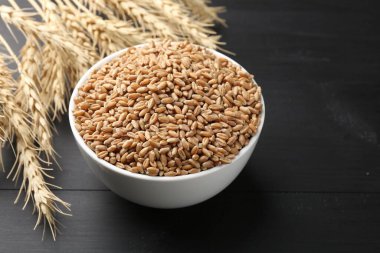 Kasede buğday taneleri ve siyah ahşap masada çiviler, yakın plan. Metin için boşluk