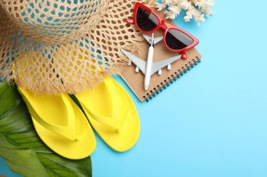 Yaz tatili zamanı. Not defteri, oyuncak uçak, yeşil yaprak ve açık mavi arka planda plaj aksesuarları, düz yatış. Metin için boşluk