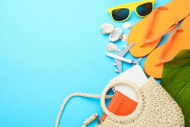 Yaz tatili zamanı. Pasaport, defter, oyuncak uçak, yeşil yaprak ve açık mavi arka planda plaj aksesuarları. Metin için boşluk