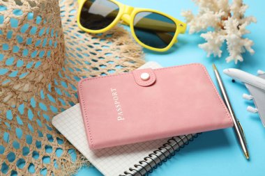 Yaz tatili zamanı. Pasaport, defter, kalem, oyuncak uçak ve açık mavi arka planda plaj aksesuarları, yakın plan.