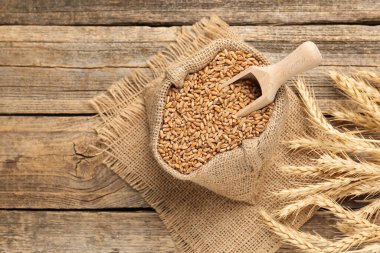 Çuval bezinde buğday taneleri, tahta masada kepçe ve çiviler, düz yatak. Metin için boşluk