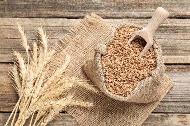 Çuval bezi torbasında buğday taneleri, tahta masada kepçeler ve çiviler.