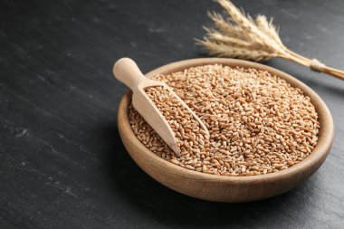 Kasede buğday taneleri, siyah masada kepçe ve çiviler, yakın plan. Metin için boşluk