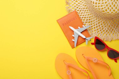 Yaz tatili zamanı. Pasaport, oyuncak uçak ve sarı arka planda plaj aksesuarları. Metin için boşluk