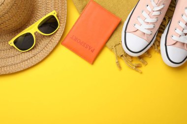 Yaz tatili zamanı. Pasaport, ayakkabı ve plaj aksesuarları sarı arka planda, düz yerde. Metin için boşluk