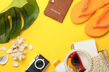 Yaz tatili zamanı. Pasaport, defter, kamera, plaj aksesuarları ve sarı arka planda yeşil yaprak. Metin için boşluk
