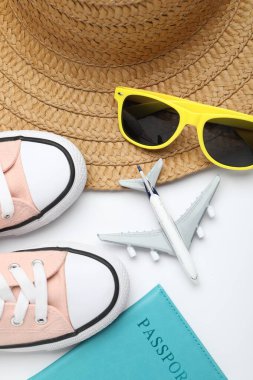 Yaz tatili zamanı. Oyuncak uçak, pasaport, ayakkabı ve plaj aksesuarları beyaz arka planda, düz konum