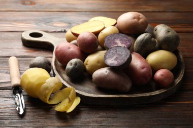 Ahşap masada farklı patates ve soyucu türleri, yakın plan.