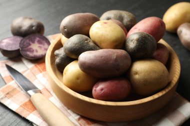 Kasede farklı patates çeşitleri ve siyah masada bıçak, yakın plan.