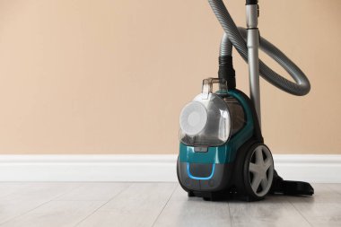 Bej duvarın yanında yerde bir elektrikli süpürge. Metin için boşluk