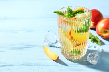 Şeftalili buzlu çay ve açık mavi ahşap masada nane şekeri, yakın plan. Metin için boşluk