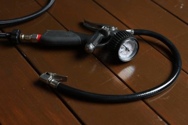 Ahşap arka planda göstergesi olan bir lastik enflasyon silahı, yakın plan.