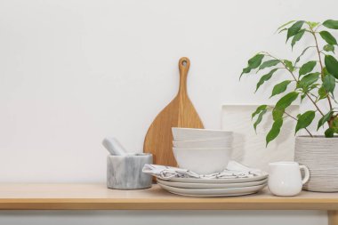 Farklı temiz beyaz bulaşık takımı, tahta kesme tahtası ve kapalı masa üzerindeki çiçek dekoru, metin için yer.
