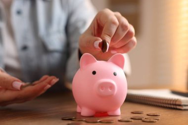 Ahşap masadaki kumbaraya para yatıran kadın, yakın plan.