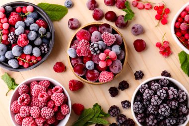 Farklı olgun donmuş böğürtlenler ve nane yaprakları açık ahşap masada, düz yatıyordu.