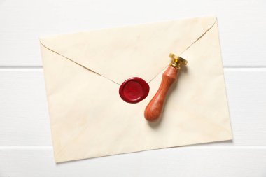 Balmumu mühürlü zarf ve beyaz ahşap masa, üst görünüm