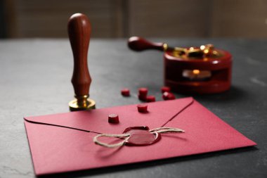 Balmumu mühürlü zarf, sicim ve damgalı siyah masa, yakın plan.