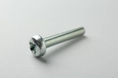 Açık gri arka planda bir metal cıvata, yakın plan. Donanım aracı