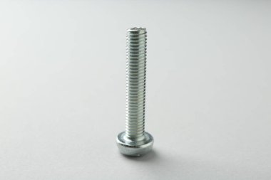 Açık gri arka planda bir metal cıvata, yakın plan. Donanım aracı