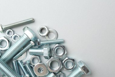 Beyaz arka planda metal cıvatalar ve fındıklar, düz yatış. Metin için boşluk