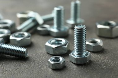 Gri masada metal cıvatalar ve fındıklar, yakın plan.