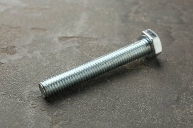 Gri masada bir metal cıvata, yakın plan.