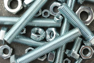 Metal civatalar ve fındıklar gri masada, düz yatıyordu.