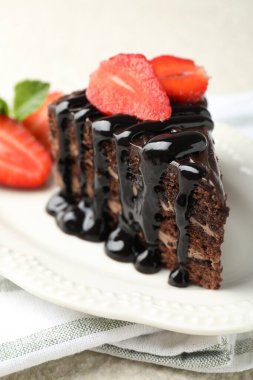 Bir parça çikolatalı kek. Masada çilek var. Yakın plan.