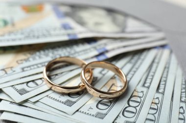 İki altın alyans, dolar banknotları ve zarf, yakın plan.