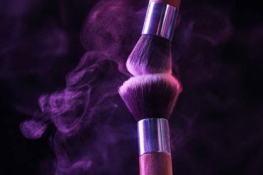 Siyah arka planda neon ışıklarda mor göz farlı makyaj fırçaları, yakın plan