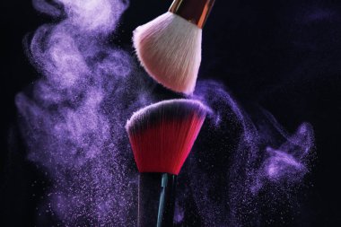 Siyah arka planda mor göz farlı makyaj fırçaları, yakın plan