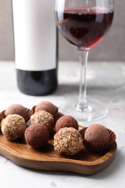 Açık gri arka planda lezzetli trüf şekerleri ve kırmızı şarap, yakın plan.