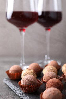 Lezzetli yer mantarı bonbonları ve gri desenli masada kırmızı şarap, yakın plan.