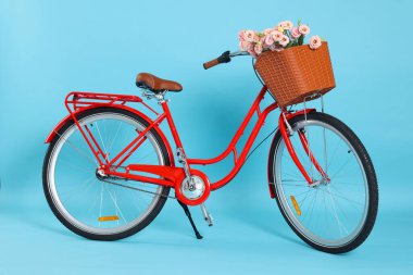 Açık mavi arka planda güzel çiçeklerle dolu bir bisiklet sepeti