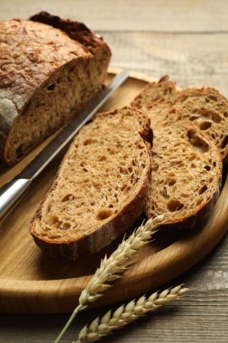 Taze ekmek parçaları, çiviler ve bıçak ahşap masada, yakın plan.