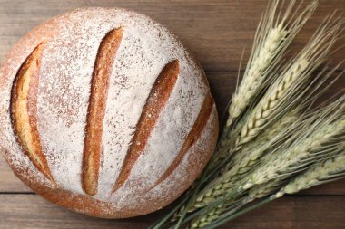 Taze ekmek ve yeşil buğday çivileri ahşap masada, düz yerde.