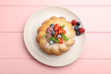 Pudra şekeri, böğürtlen ve nane şekerli nefis kek pembe ahşap masa, üst görünüm