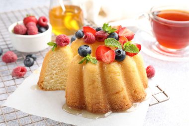 Açık gri masada böğürtlenli kek, bal, nane ve çay, yakın plan.