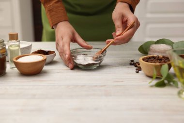Doğal temizlik yapıyorum. Kahveyle şekeri karıştıran kadın beyaz tahta masada, yakın plan.
