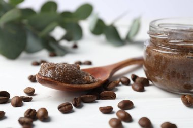 Doğal vücut fırçası, kahve çekirdekleri ve okaliptüs dalları beyaz ahşap masada, yakın plan.