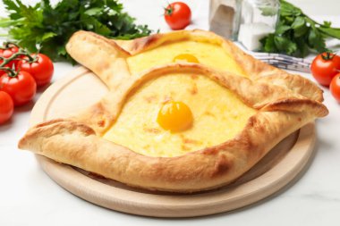 Peynirli, yumurtalı, domatesli, maydanozlu ve baharatlı khachapurili beyaz mermer masa, yakın plan.