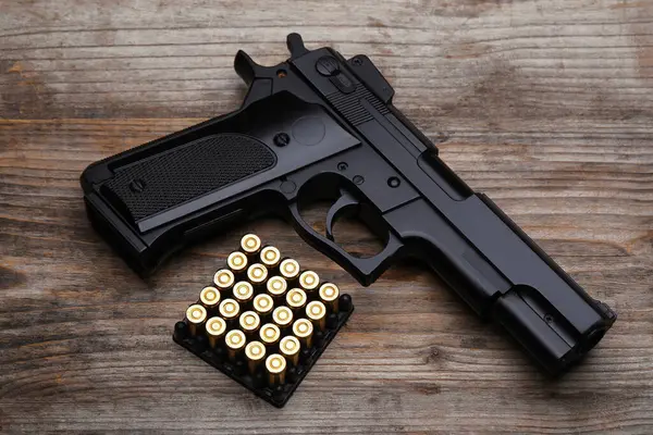 Tahta masada metal mermiler ve tabanca, düz yatıyordu.