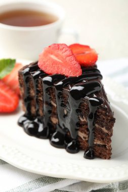 Çilek ve çayla servis edilen bir parça çikolatalı kek, yakın plan.