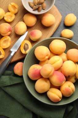 Taze kayısılar kasede, çekirdekler ve bıçak siyah masada, düz yatıyordu.