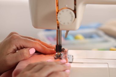 Atölyede dikiş makinesi ve kumaşla çalışan bir kadın.